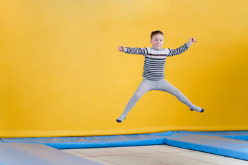 Happy smiling small kid jumping on indoors trampoline in entertainment center