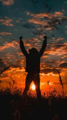 Silhouette of a cheering individual against the sunrise.