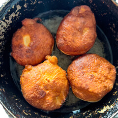 Homemade fried donut pastries cooking in a rustic pan, traditional hungarian dish named "f&aacute;nk"