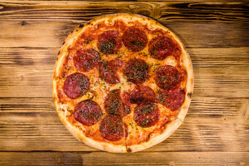 Pizza with salami sausage and parmesan cheese on a wooden table. Top view