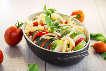 raw zucchini and tomatoes sliced and prepared for baking in a ceramic dish, vegetable appetizer