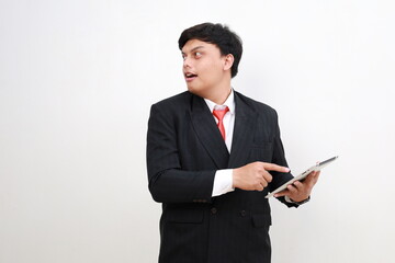 Young asian businessman standing using tablet computer while looking advertising sideways isolated on white background