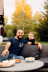 Radiant father and child on the backyard patio, ready for a meal together, summer days, family outdoor