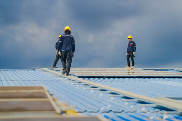 Worker Technicians are working to construct solar panels system on roof. Installing solar photovoltaic panel system. Men technicians walking on roof structure to check photovoltaic solar modules.