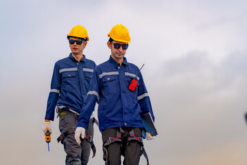 engineer man inspects construction of solar cell panel or photovoltaic cell by electronic device. Industrial Renewable energy of green power. factory worker working on tower roof.