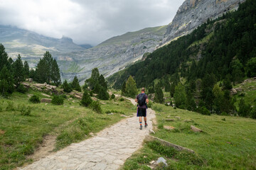 Fototapeta premium Hiker walking on a stone path in a mountainous landscape of Monte Perdido, Spain