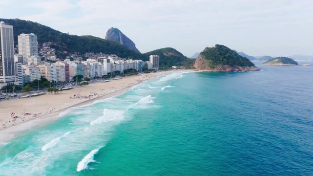 Drone shot of Copacabana Beach in Rio de Janeiro, Brazil, with a view of the ocean and surrounding mountains.