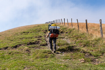 Hiker with heavy backpack ascends a hill. GR11. Navarrese Pyrenees