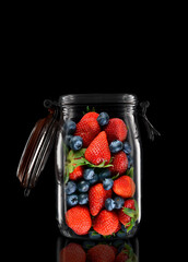 A glass storage or canning jar isolated on black with reflection, with lid open.