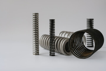 Different types of springs or coil springs on a white background. Spare parts of the engineering industry. 