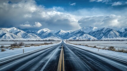 Scenic asphalt highway heading into the snowy mountains with cloudy skies, ideal for travel themes.