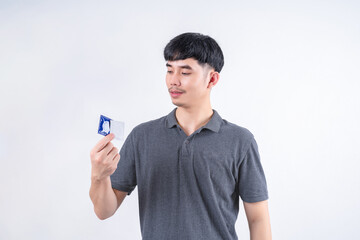 Portrait of handsome Asian man holding condom with happy smiling face. Medical concept, health care...