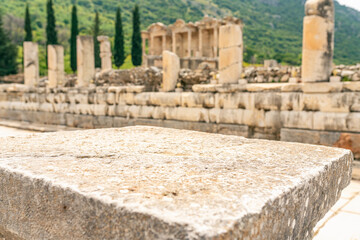 Fototapeta premium Ancient marble column as podium with background of ruins antique town. Pedestal platform for show product placement