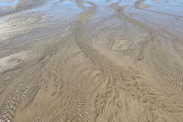 Sea water draining back to the ocean creating a ripple effect abstract background of the seaside beach
