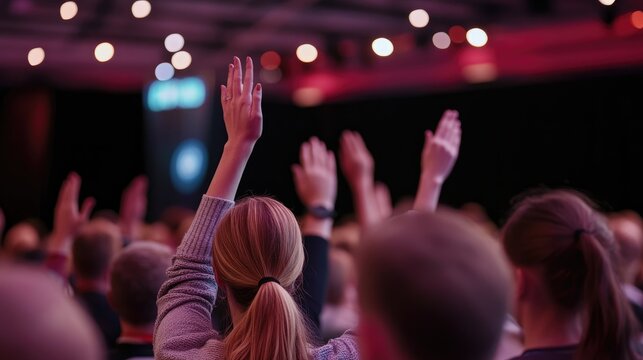 Backside perspective of attendees raising hands at a conference