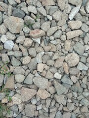 The background is stones of different sizes. Rubble, stones in close-up. Background, place for text. Background for the text. Texture. A road made of stones. A pile of rubble.