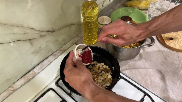 Chef adds tomato paste and water to sauteing vegetables in a pan. Detailed cooking tutorial for making a delicious sauce