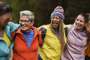 Group of multi generational women having fun together during hiking trip at mountain forest - Multiracial female friends walking outdoor - Sport and weekend acitvities - Focus on the blond woman