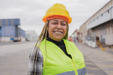 Black female dock worker control loading containers box from cargo at warehouse container yard - Logistic shipping yard concept - Focus on face