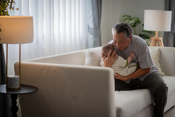 A man is holding a baby on his lap. Scene is happy and joyful