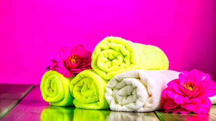 Fototapeta premium Neon-colored towels with pink flowers on a matching pink background - perfect for bold spa ads, vibrant home decor, beauty visuals