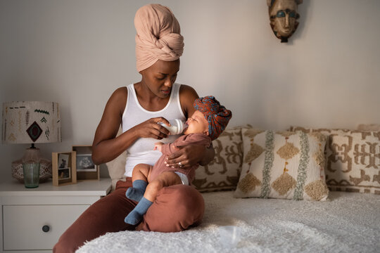 Candid mother feeding tired newborn