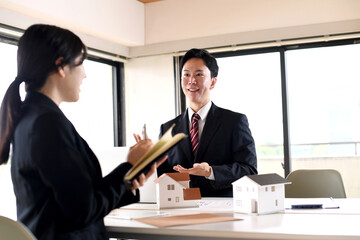 住宅模型を使い会議をする若い男女の会社員
