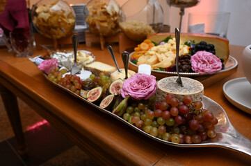 cheese and wine,  table setting, cheeses and fruits, fresh grapes, cheeses, green grapes,  appetizers, snacks, artisanal cheese, gourmet cheese board with figs, grapes, and roses in a silver 