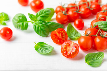 Fresh cherry tomatoes and fresh green basil on a textured background. Tomato sauce. Vegan. Ingredients for salad. Organic food. Place for text. Copy space.