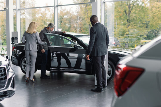 Car dealership employee presents vehicle potential buyer