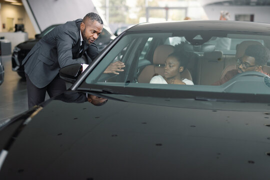 Car dealer showing automobile car shop to buyers