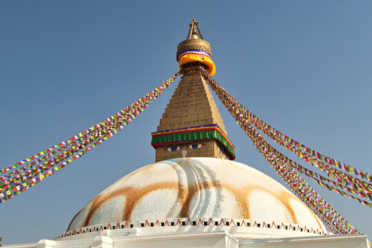 The upper part of the Boudhanath Stupa, many colorful prayer flags are attached to it, Kathmandu, Nepal