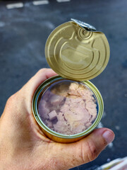 Can with tuna in oil in the hand.