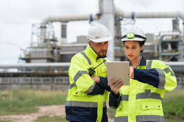Male and female petrochemical engineers with tablet working at petroleum refinery. Workers survey...