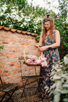 woman holding basket with lilacs in her garden