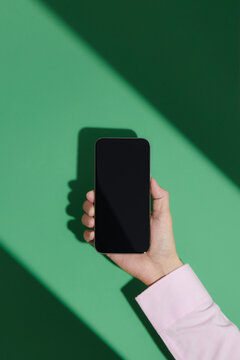A woman's hand holding blank screen mobile phone isolated over g