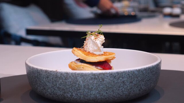 Gourmet dish of stacked pancakes with fruit and whipped cream served in elegant restaurant setting, fine dining and culinary arts.