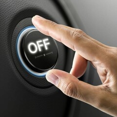A person's fingers pointing towards a luminous button with the text OFF