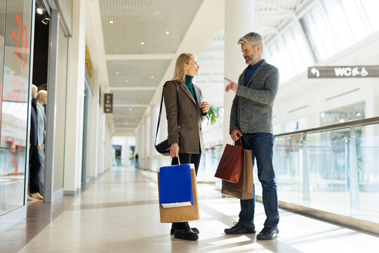 Man telling to smiling woman at mall on weekend or in free time