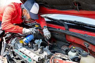 Adult man, knowledgeable about automobiles, works on his car