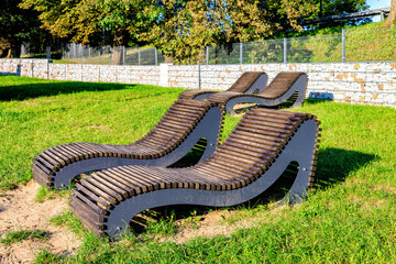 Four stationary sun loungers on the city beach. Green lawn.