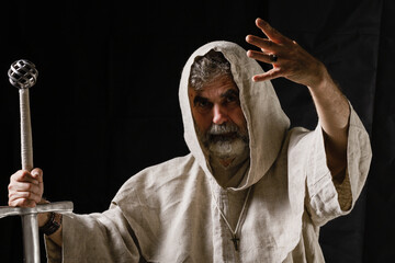 A warrior monk holds a sword in one hand and gesticulates furiously with the other.