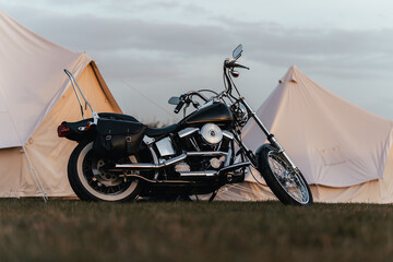 Chopper style motorcycle parked next to large white tents, custom vintage motorbike cruiser