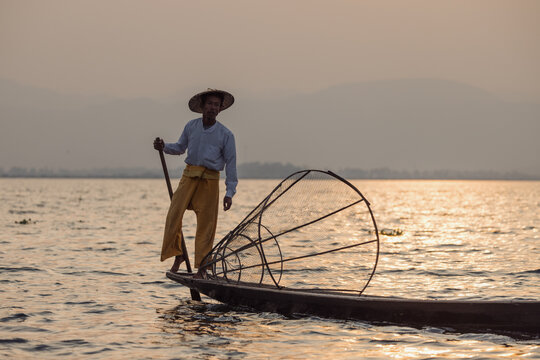 Traditional Fisherman Leg-Rowing on Boat at Sunset