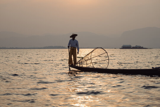 Traditional Fisherman Leg-Rowing on Boat at Sunset