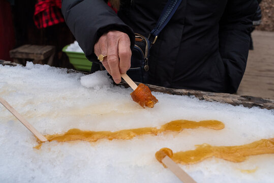 Senior woman hand with ring rolling maple taffy