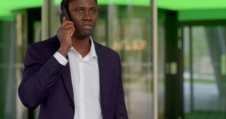 A young professional man is actively engaging in an important phone conversation outside a sleek building use 5g - Powered by Adobe
