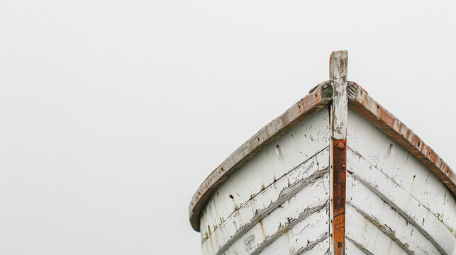 Close-up of the weathered wooden bow of an old boat against a blank white background, showcasing its rustic textures and peeling paint.