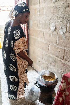 Senegalese woman cooking traditional food on charcoal stove