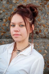 Red-haired girl in a formal outfit in front of a stone wall